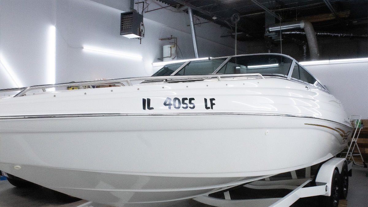 Custom Boat Registration Numbers (2 - Pack) - Rising Sun Decals - White boat with a license plate in a indoor setting
